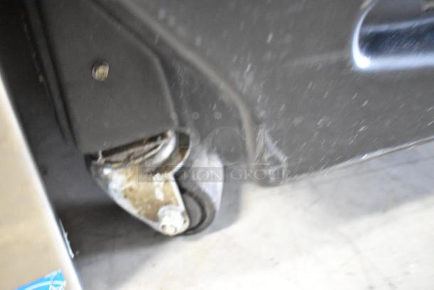 Close-up of a commercial caster wheel on an Imbera G319 reach-in cooler, showing moderate wear and sturdy construction.