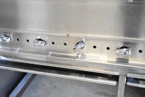 Stainless steel commercial gas grill with control knobs and commercial casters, in good condition.