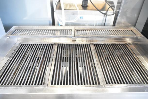 Stainless steel commercial gas grill on commercial casters, featuring multi-section grilling surfaces, in good condition.