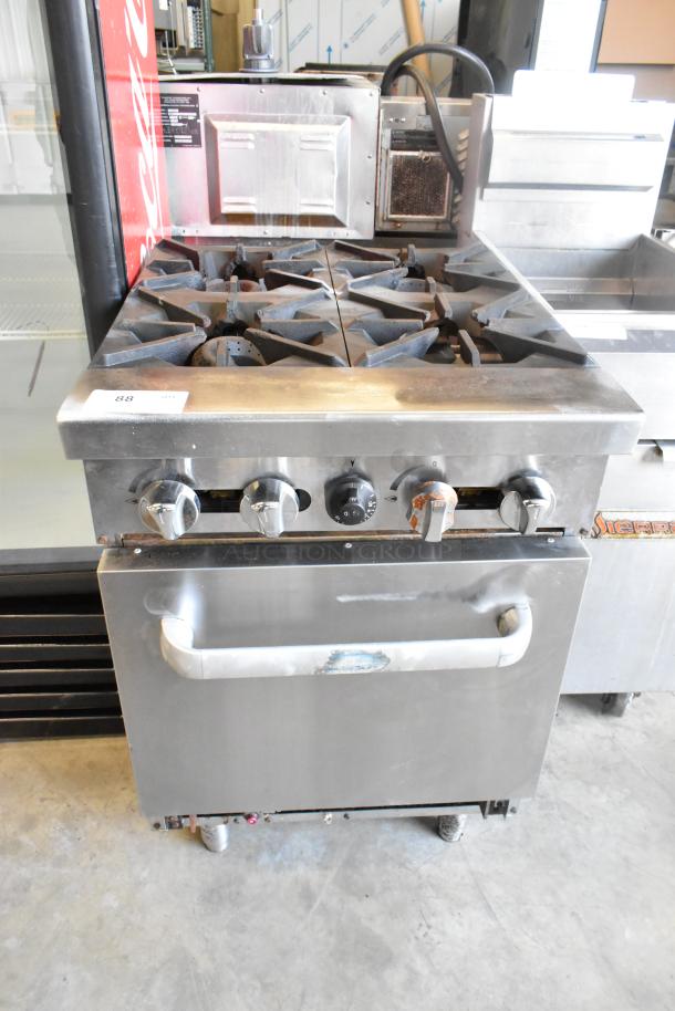 Stainless steel commercial gas-powered 4 burner range with oven, features sturdy construction, in used condition, visible wear.