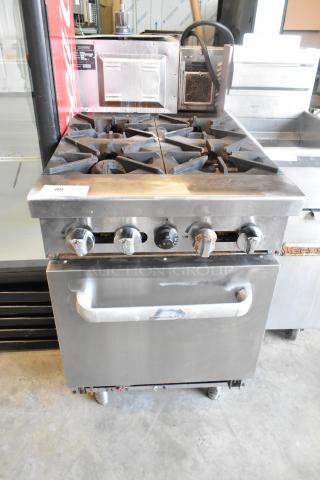Stainless steel commercial gas-powered 4 burner range with oven, features sturdy construction, in used condition, visible wear.