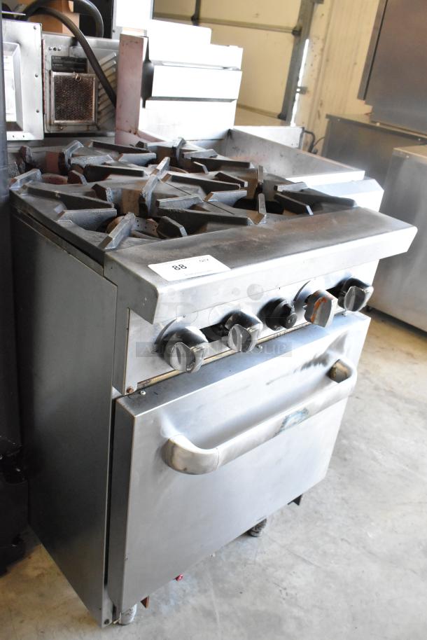 Stainless steel commercial 4-burner gas range with oven. Features sturdy knobs, visible wear, and commercial power.