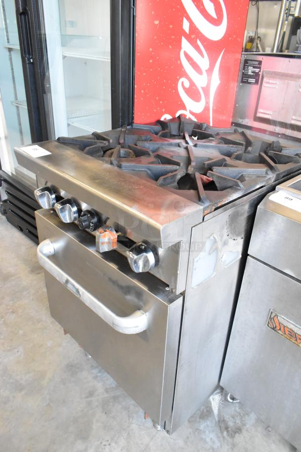 Stainless steel commercial gas-powered 4 burner range with oven, featuring control knobs and used condition.