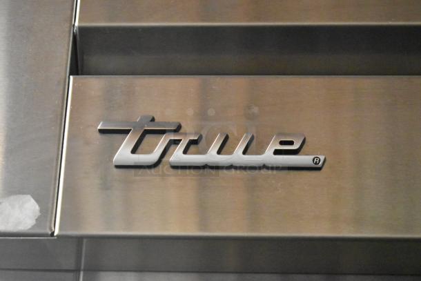 True logo on stainless steel panel of 2017 True STR1R-1S-HC commercial cooler. Scratch visible on surface.