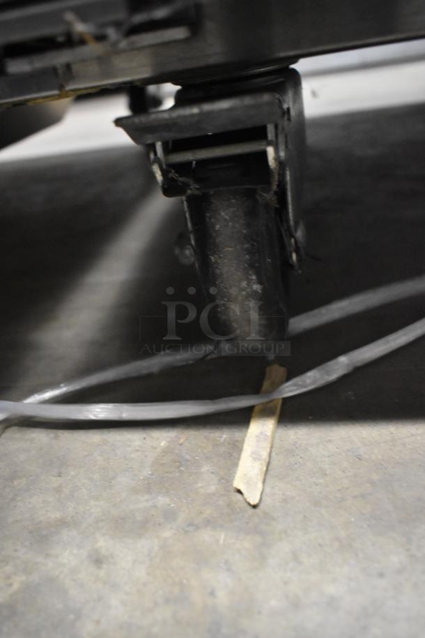 Close-up of a caster wheel on a 2021 Atosa MBF8002GR stainless steel commercial freezer, showing ground contact.