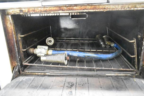Garland stainless steel commercial gas oven interior, showing wear with visible pipes and fittings.