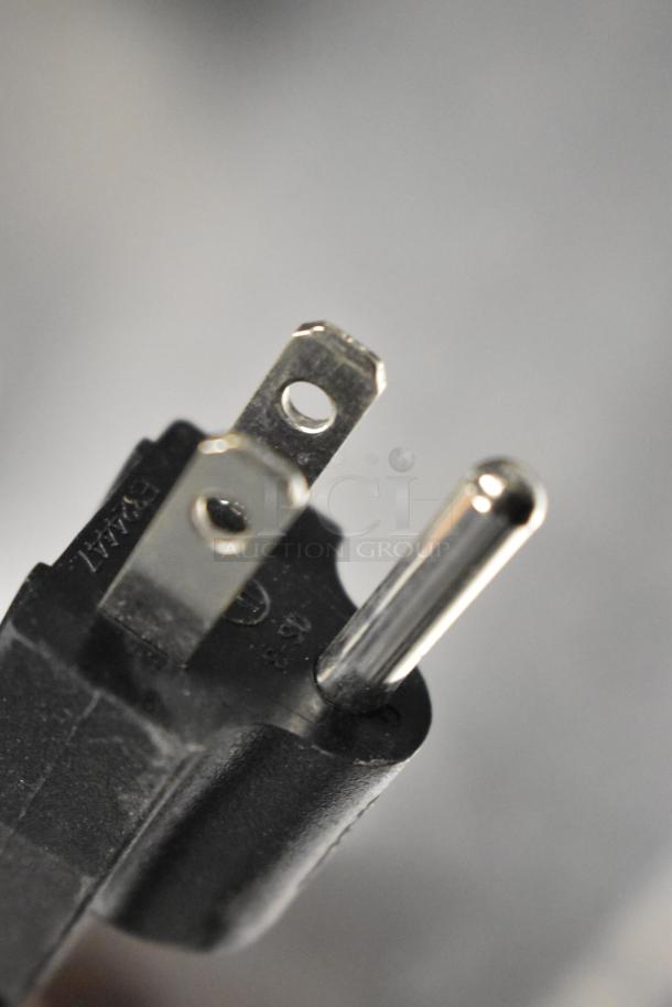 Close-up of a three-prong electrical plug against a blurred background.