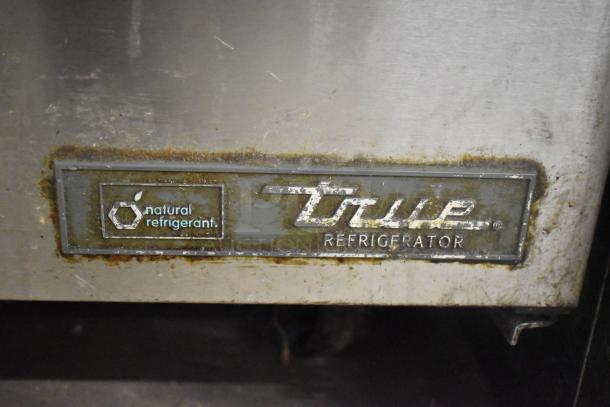 True TSSU-60-10-HC prep table tag, showing "natural refrigerant" marking, on worn stainless steel surface.