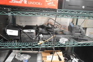 Eight electronic items including SNBC BTP-M300, Epson M267D, Epson M188B receipt printers, Netgear GS308PP switch, visible in a storage setting.