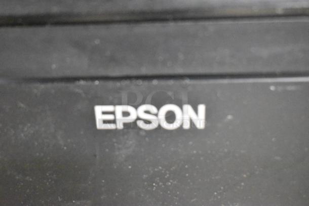 Close-up of Epson label on a receipt printer, part of an auction lot including multiple receipt printers and a Netgear switch.