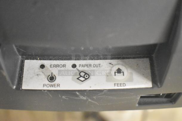 Close-up of a label showing controls for power, error, paper out, and feed on a receipt printer.