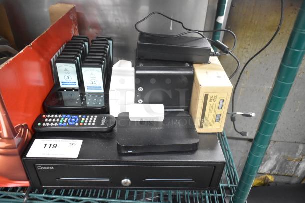 Various tech items including Toast metal cash drawer, Cisco router, Toast Go 2 tablet, TP200 printer, and pager system with 19 pagers, all in used condition.