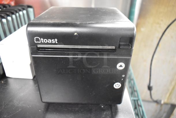 Toast TP200 receipt printer, black, showing minor wear. Features brand logo, power button, and feed button.