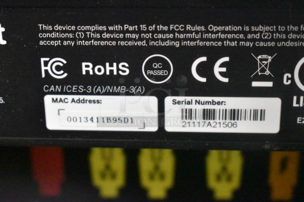Close-up of device labels showing FCC, RoHS compliance, and QC passed. Includes MAC address and serial number details.
