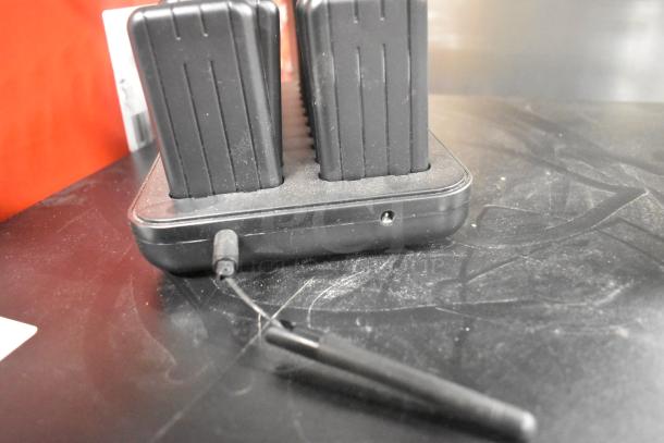 Pager system charger with 19 pager slots, black, in used condition, showing dust and a visible power cable.