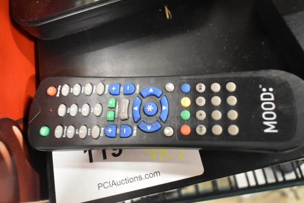 Remote control labeled "MOOD" with multi-colored buttons on a black surface, typical wear visible.