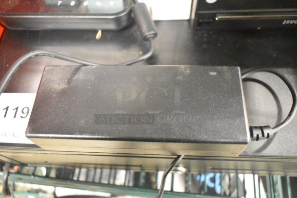 Assorted tech gear: Toast metal cash drawer, Cisco router, Toast Go 2 tablet, TP200 printer, pager system with charger and 19 pagers.