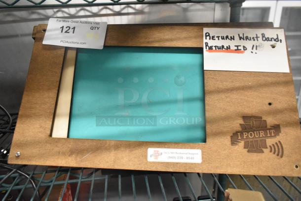 Wooden display frame with "I Pour It" logo and message about returning wrist bands. Auction item tag with lot number 121.