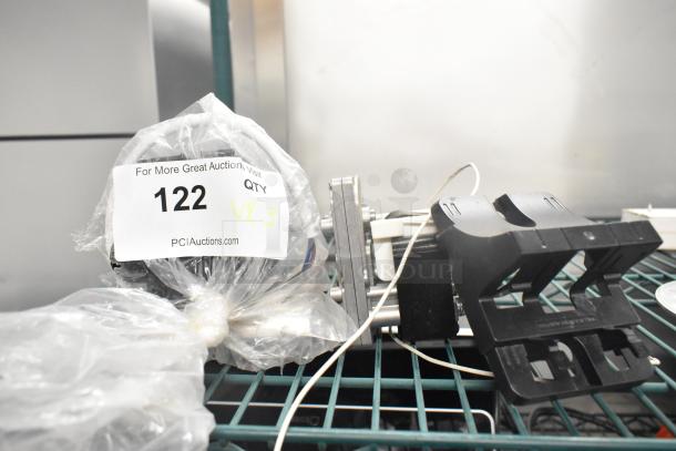 Three assorted items including a motor, auction label with quantity 3, in used condition on a wire shelf.