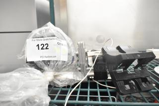 Three assorted items including a motor, auction label with quantity 3, in used condition on a wire shelf.