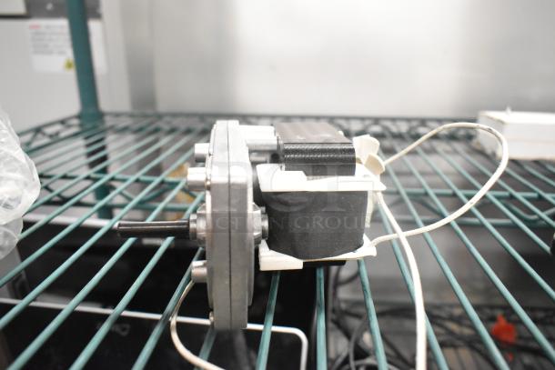 Electric motor with visible wiring on a metal shelf, showing a sturdy, compact design, in good condition for auction.