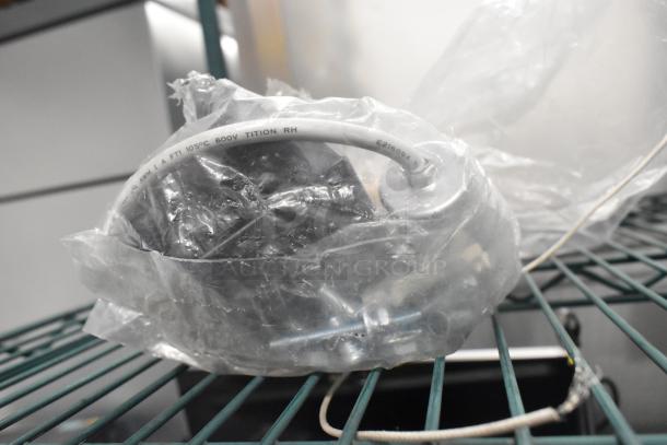 Plastic-wrapped motor on shelf; visible label reads "105°C 600V TITION RH." Auction includes three varied items.