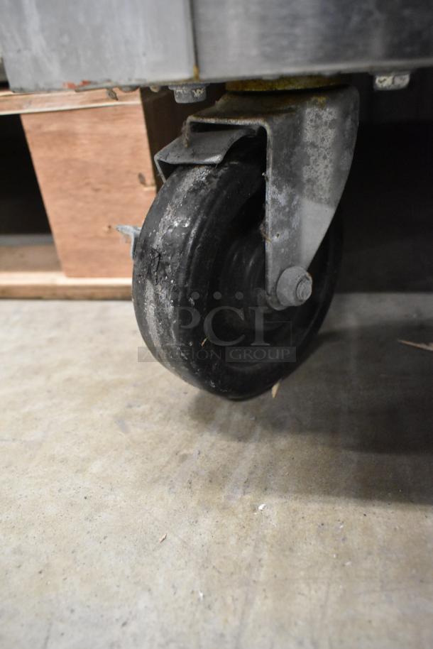 Close-up of a commercial caster on a Traulsen G22010 stainless steel freezer. Durable, heavy-duty design.