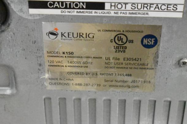 Keurig K150 coffee machine label showing model, 120V 1400W power details, UL and NSF certification, serial number J0170906.