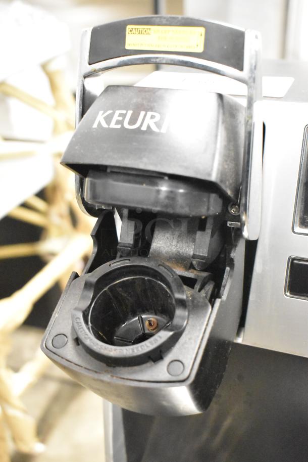 Keurig K150 countertop coffee machine, 120 Volts, 1 Phase, visible caution label, used condition, open brew chamber.