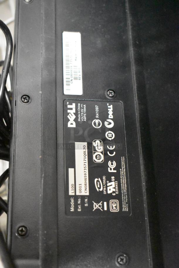 Close-up of a Dell model L100 label on a black device, showing serial number, made in China. Part of auctioned tech lot.