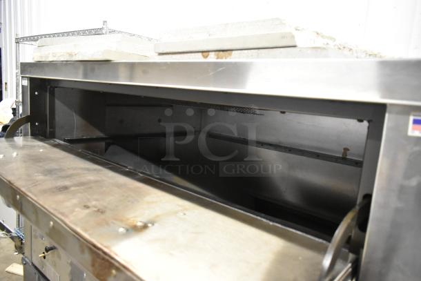 Peerless stainless steel commercial 2 deck pizza oven on metal legs, showing interior, robust design, and durable materials.