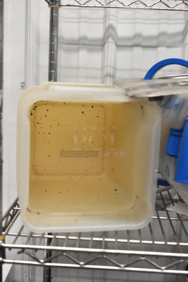 Plastic poly bin with minor surface dirt, open lid stored on a metal shelf, part of a mixed auction lot.
