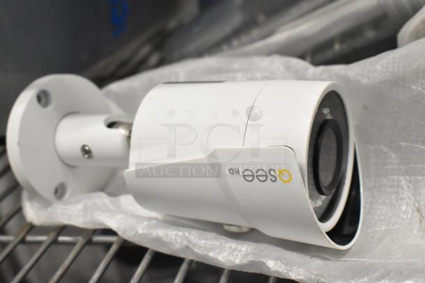 A white Osee HD security camera lies sideways, featuring a cylindrical design with mounting bracket, on metal shelving.