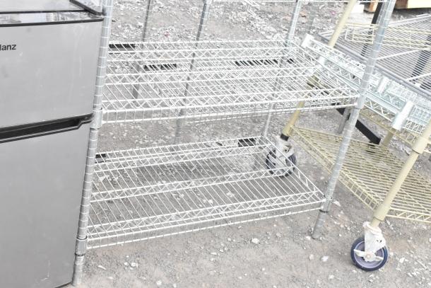 Two metal wire shelving units on casters, suitable for storage. Good condition. Buyer must dismantle and consider freight.