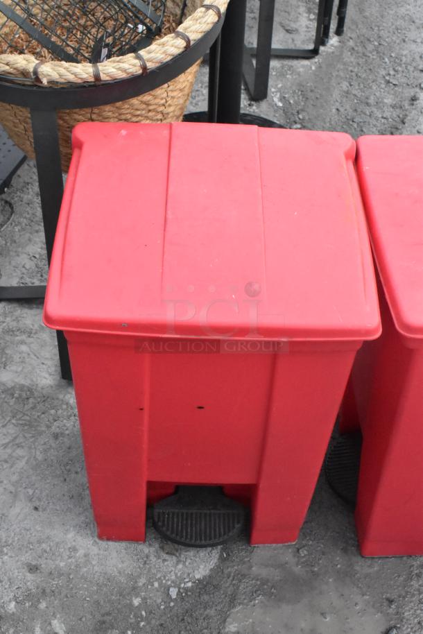 2 red poly foot pedal trash cans with contents, including a fire extinguisher and fan. Buyer pickup required.