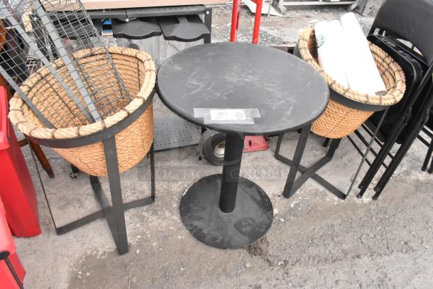 Round black table and two wicker basket stands with black metal frames. Table labeled "163". Slight wear visible.