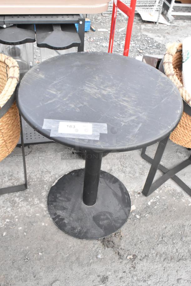 Black round table with pedestal base, showing surface wear. Includes two basket stands. Auction label marked "163."