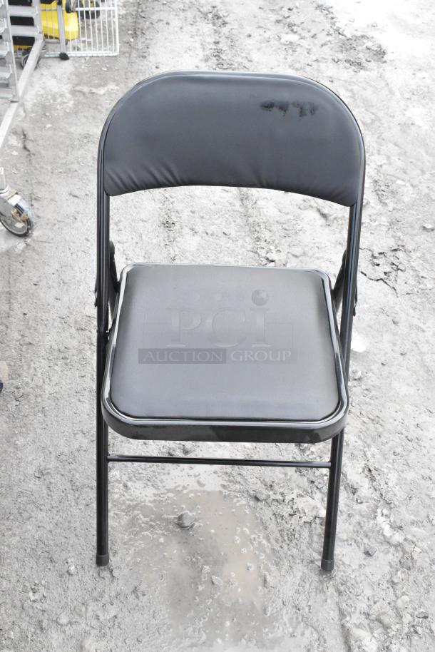 Black metal folding chair, padded seat and backrest, minor wear on surface, suitable for indoor or outdoor use.