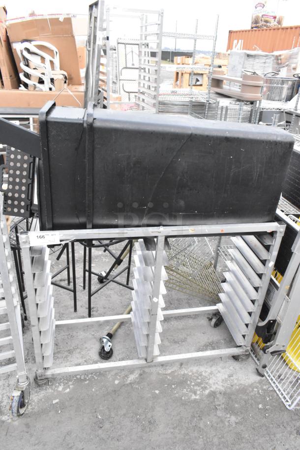 Metal commercial double pan transport rack on casters, includes two black trash cans. Slight wear evident, sturdy build.