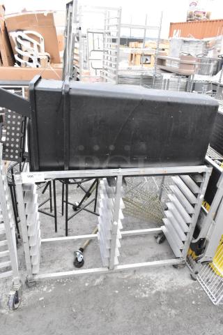 Metal commercial double pan transport rack on casters, includes two black trash cans. Slight wear evident, sturdy build.