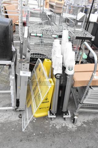 Seven items including a cup dispenser, ladder, and wet floor caution cones. Items displayed on metal shelves.
