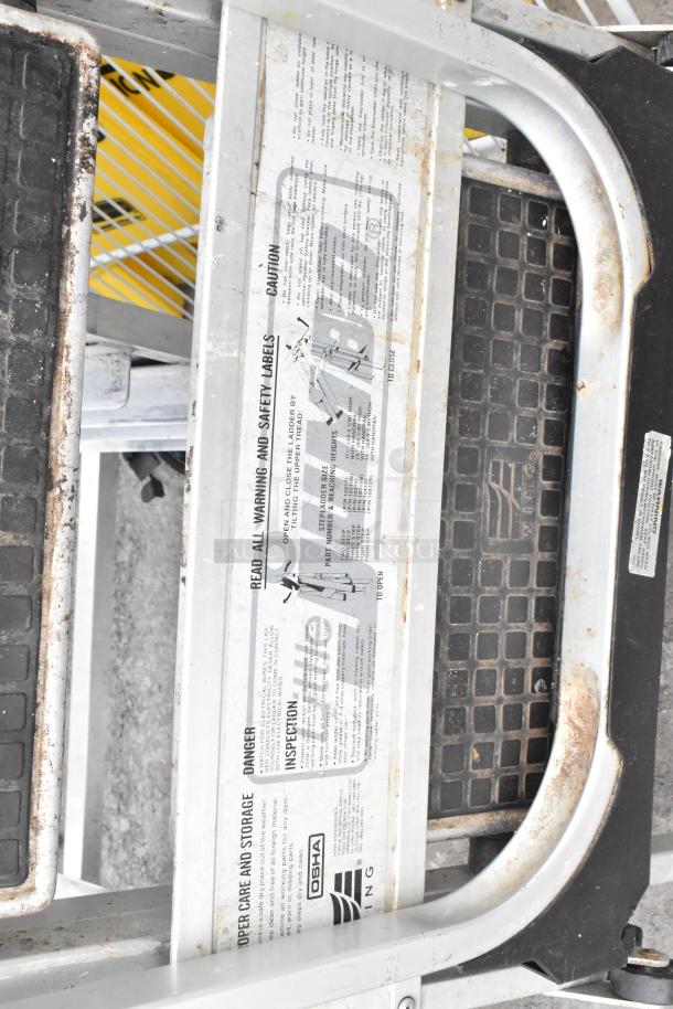 7 various items including a cup dispenser, ladder with safety labels, and wet floor caution cones. Sold as a lot, 7x bid.