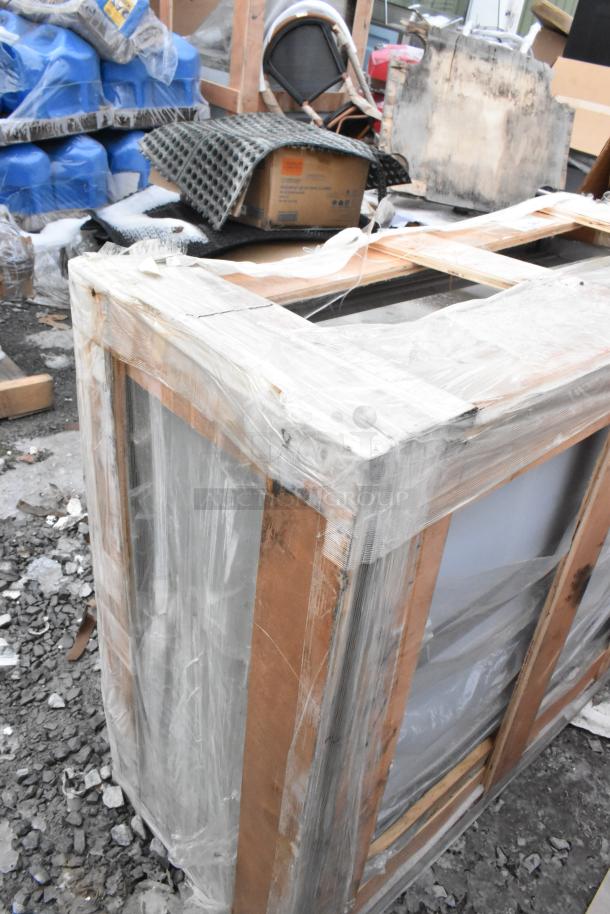 Alt text: Brand new Regency 600WCS1536 36" stainless steel wall cabinet with sliding doors, wrapped and crated, showing minor scratches and dents.