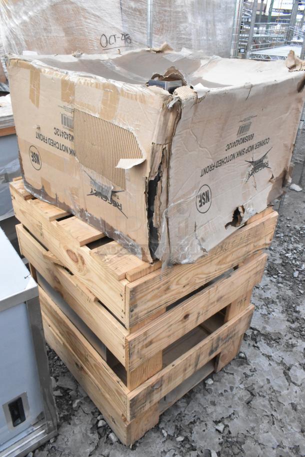 Two brand new Regency 600SM242412C 16-gauge stainless steel corner mop sinks in damaged packaging.