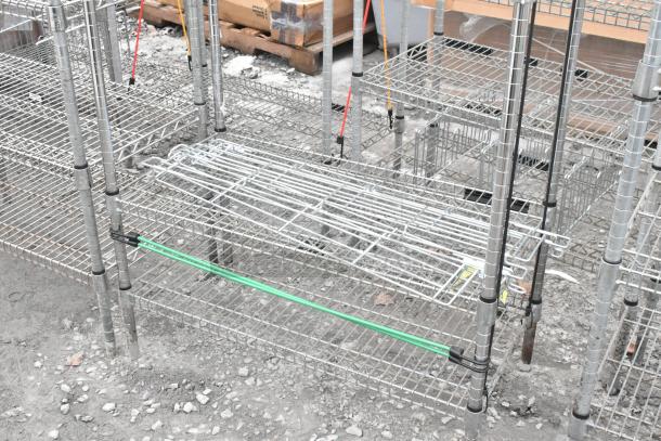 Two chrome finish wire shelving units on a gravel surface, dismantled. Buyer must dismantle; consider freight charges.