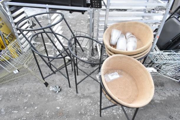 5 black metal basket stands with 4 woven baskets, some holding cups. Each basket is labeled "185 qt." Suitable for display.