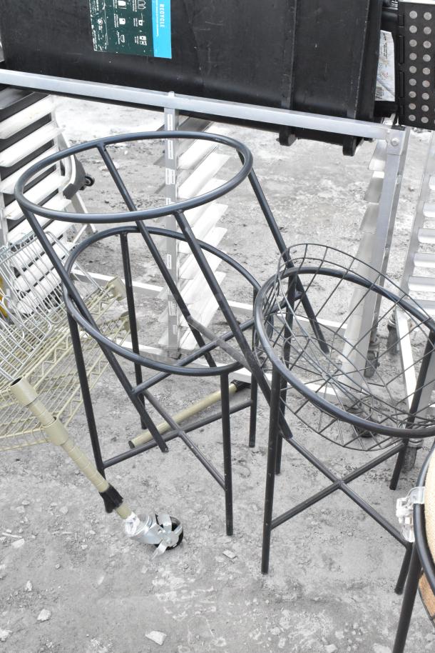 Metal basket stands, lacking baskets, featuring sturdy construction. Includes four legs and circular frames. Condition appears used.