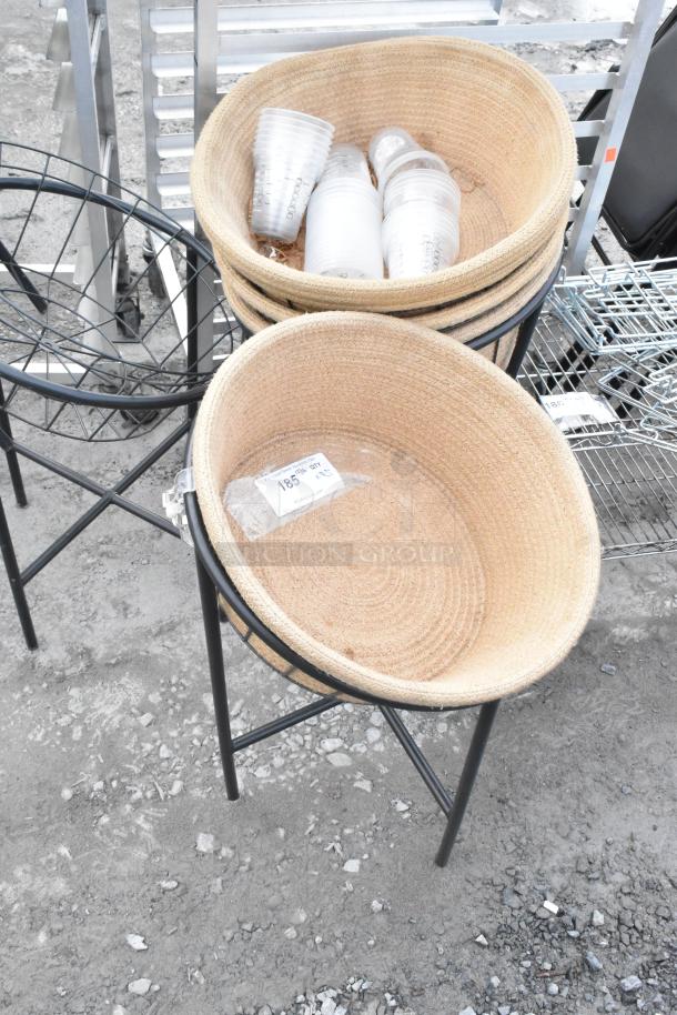 5 basket stands with 4 woven baskets each on metal frames. Includes label indicating "185 lb" capacity. Ideal for display.