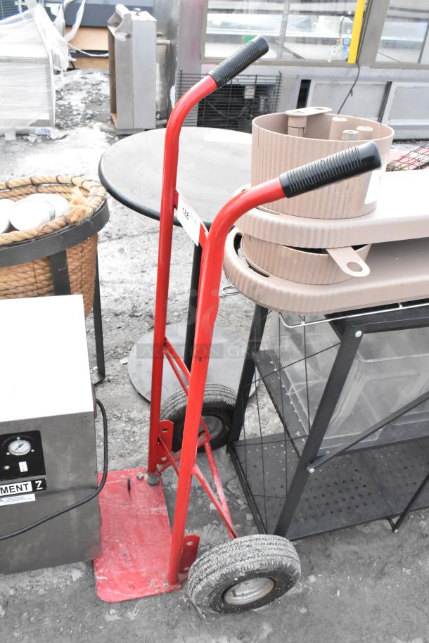 Red metal furniture dolly with rubber handles and large wheels, shows signs of use, labeled as item 189.
