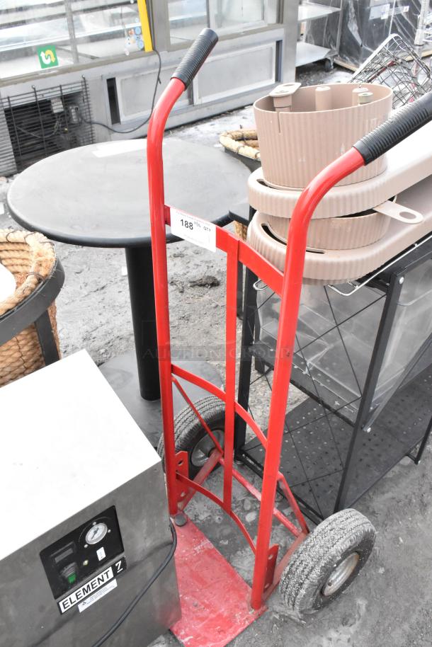 Red metal furniture dolly with black handles and wheels, visible label shows "188" indicating quantity or price, used condition.